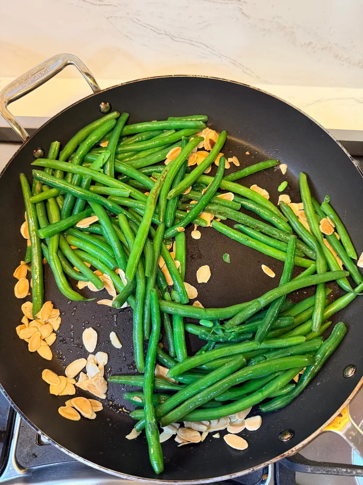 Saucepan with green beans and toasted sliced almonds.