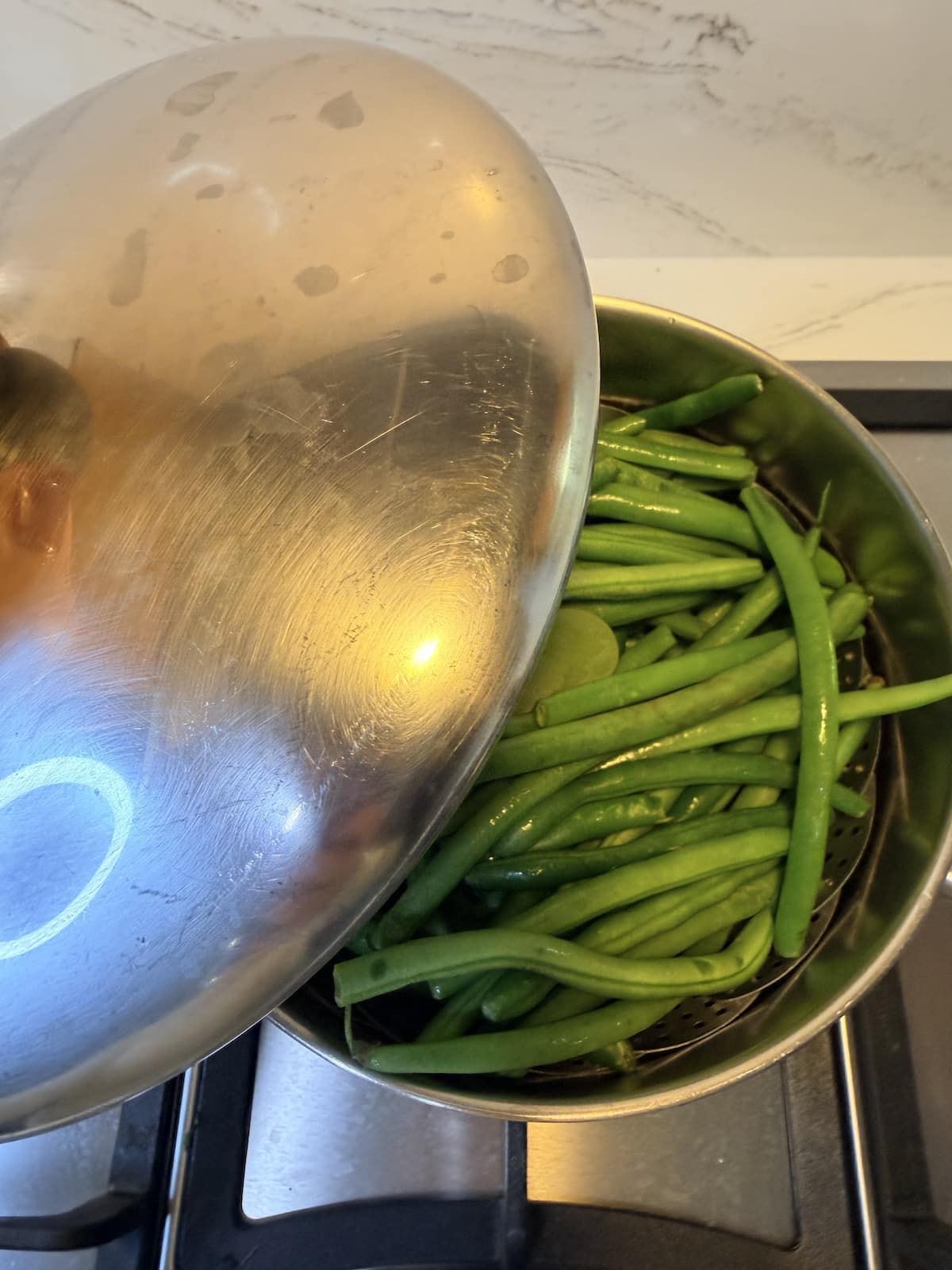 Green beans steaming in a pot over the stovetop.