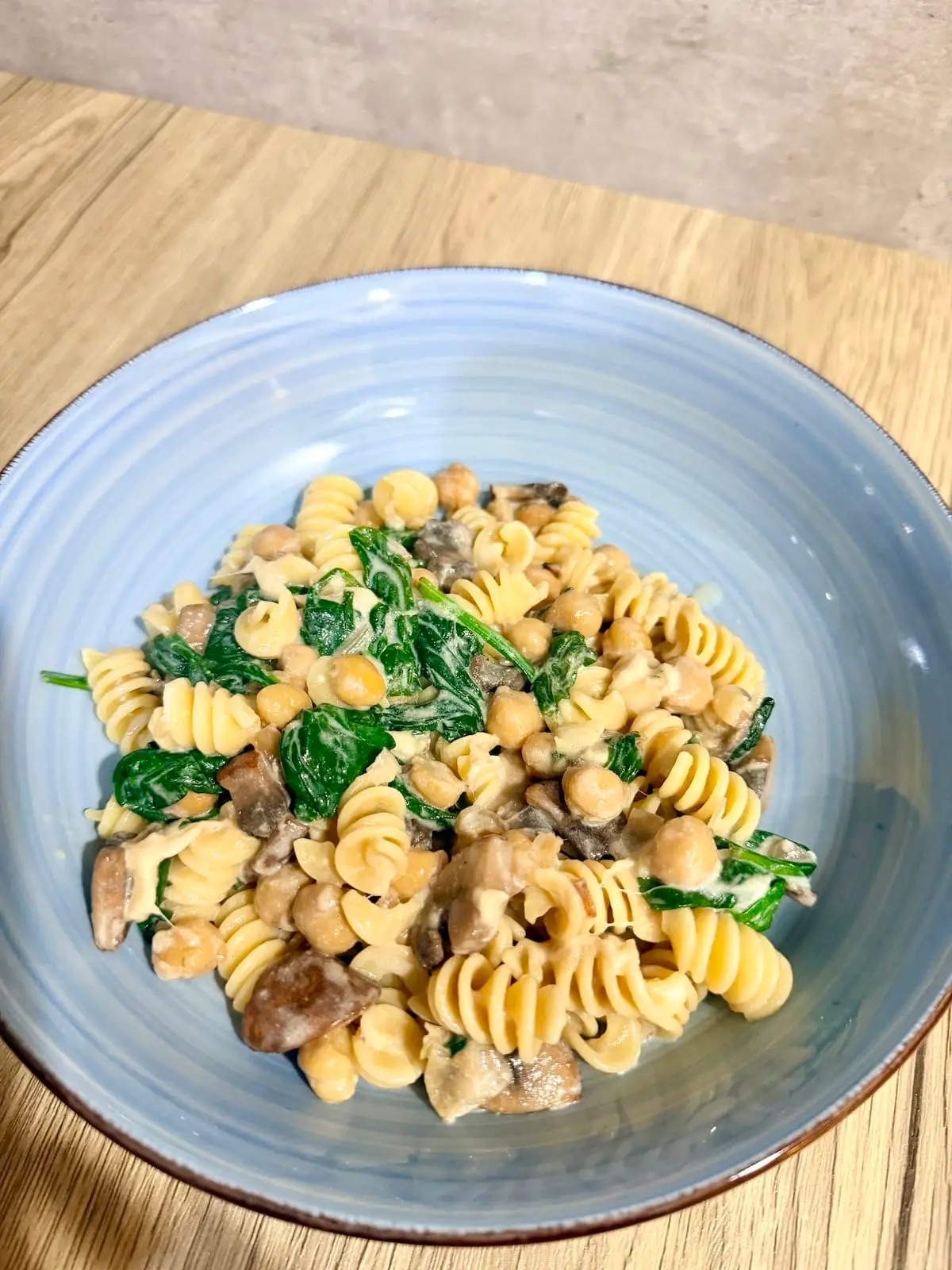 Creamy Vegetarian Pasta in a blue pasta bowl atop a wooden surface.
