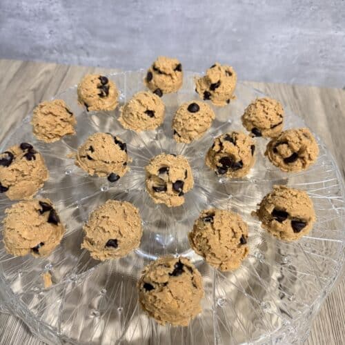 protein cookie dough balls atop a fancy crystal cake stand.