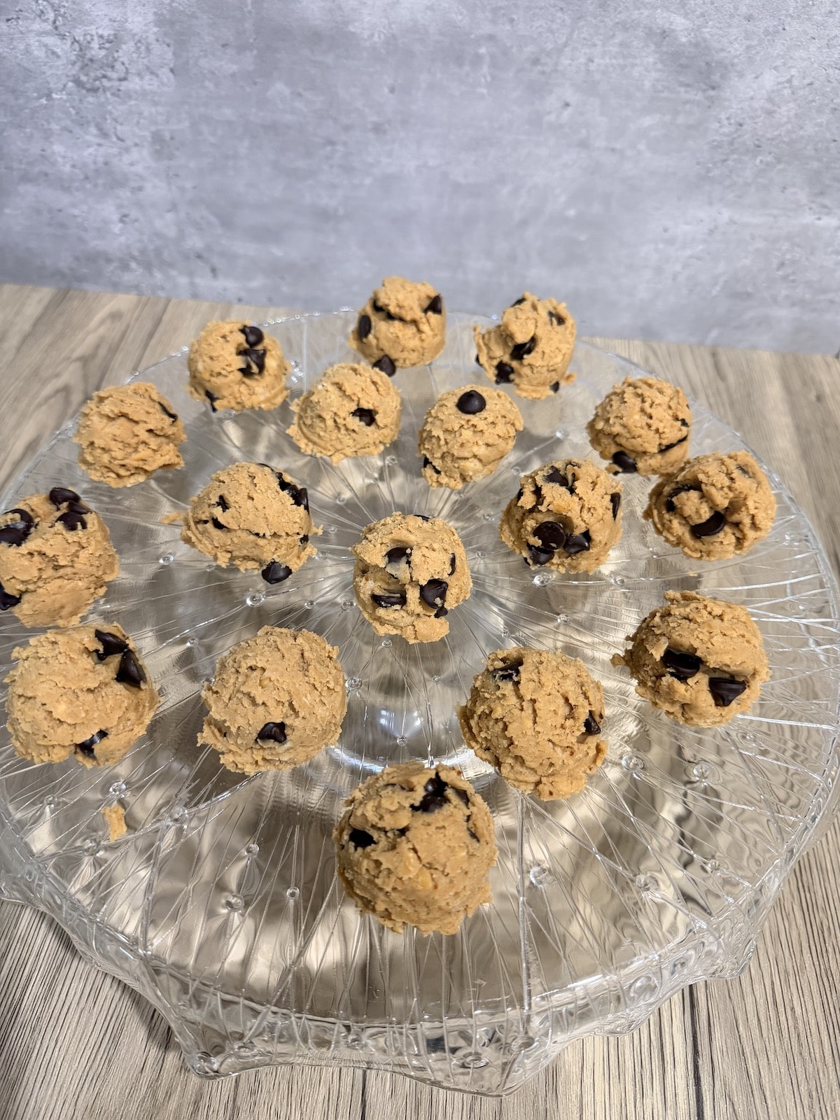 protein cookie dough balls atop a fancy crystal cake stand.