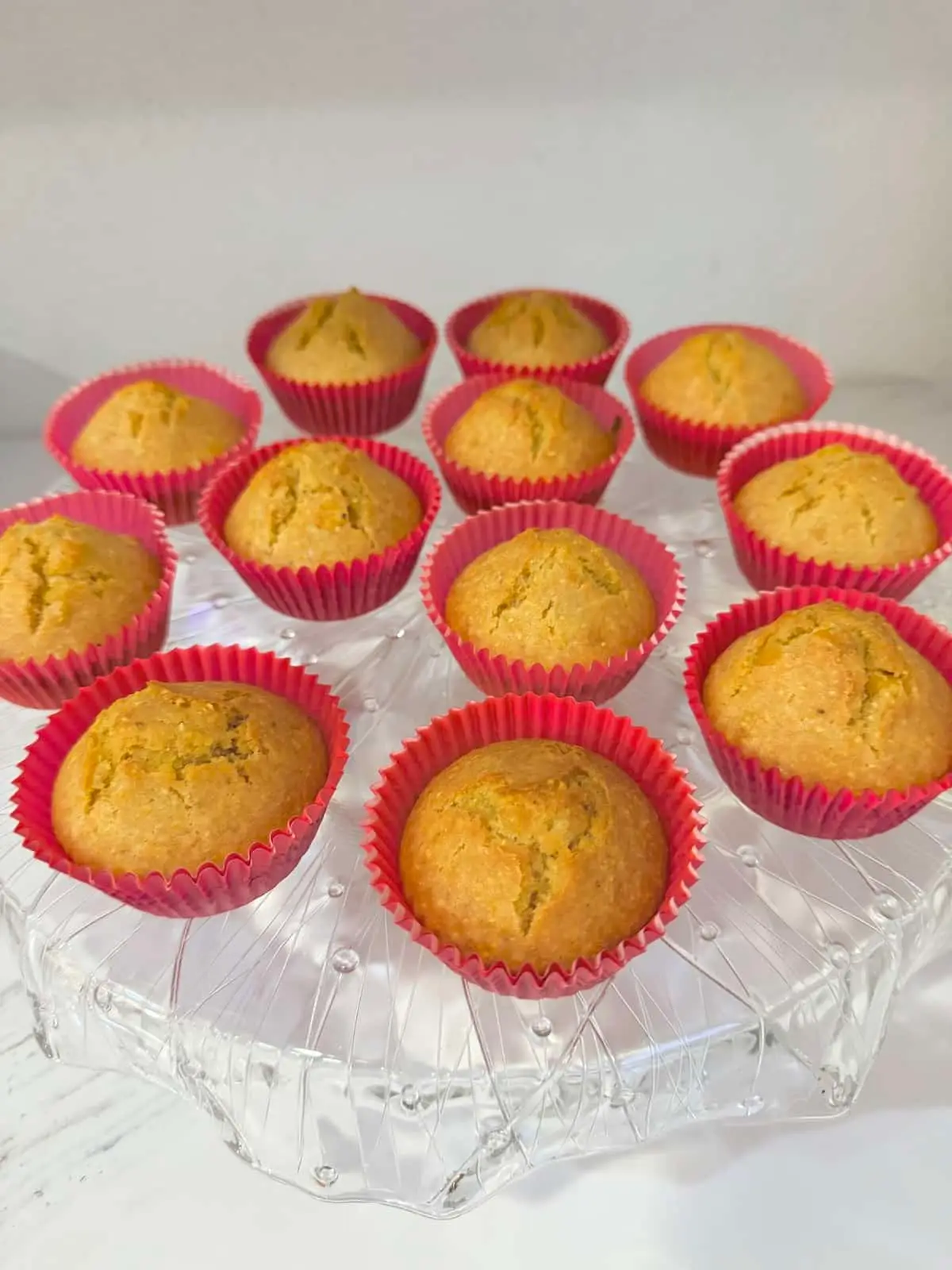 buttermilk cornbread muffins in pink muffin cups atop a crytal platter.