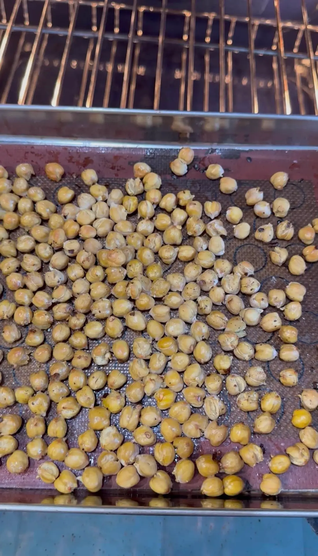 roasted chickpeas atop a silicon lined baking sheet in the oven.