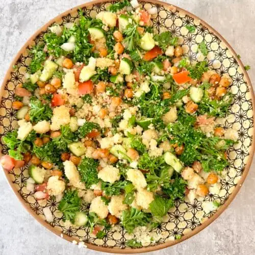 Tabbouleh couscous salad in a large patterned bowl atop gray surface.